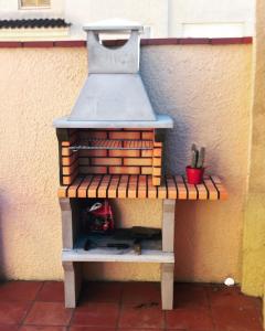 un gril à pattes assis sur un banc à côté d'un mur dans l'établissement CA LA CRISTI - 2 terrazas, piscina, wifi y barbacoa, à L'Escala 4 autres photos