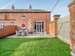 a brick house with a fence in the yard at Norfolk Cottages - The Ostlery in Smallburgh