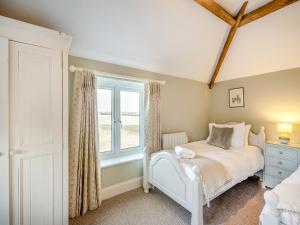 a bedroom with a white bed and a window at Norfolk Cottages - The Ostlery in Smallburgh