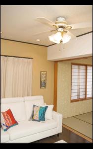 - un salon avec un canapé blanc et un ventilateur de plafond dans l'établissement They are NOT HOUSE - Vacation STAY 86998, à Okinawa