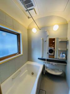 uma casa de banho com uma banheira, um WC e uma janela. em Swiss Chalet - Vacation STAY 11450v em Iida