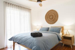 a bedroom with a bed with blue sheets and a window at La Boheme Tootgarook in Tootgarook