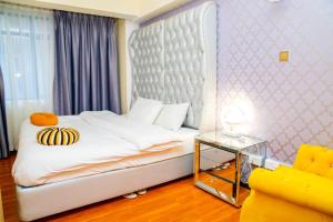 - une chambre avec un grand lit et un canapé jaune dans l'établissement Lux Suites Marcus Garden Apartments kilimani, à Nairobi