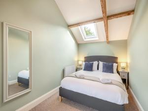 a bedroom with a bed and a mirror at Norfolk Cottages - The Coach House in Smallburgh