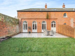 a brick building with white doors and chairs in the yard at Norfolk Cottages - The Coach House in Smallburgh