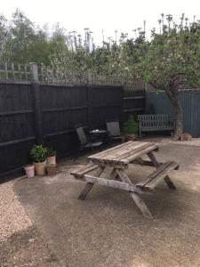 une table de pique-nique et un banc dans une arrière-cour avec une clôture dans l'établissement Herb Garden Bungalow, à Nazeing