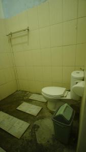 a dirty bathroom with a toilet and a trash can at mimi kuta homestay in Kuta Lombok