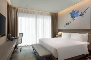 Habitación de hotel con cama blanca grande y escritorio. en Dusit Thani Laguna Singapore en Singapur