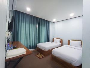 Habitación con 2 camas, escritorio y TV. en ເຮືອນພັກບີວີ(BV Guesthouse), en Ban Thôngchai-Tai
