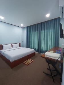 a bedroom with a bed and a desk and a television at ເຮືອນພັກບີວີ(BV Guesthouse) in Ban Thôngchai-Tai