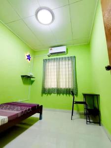 a green room with a bed and a window at Izzara Iskandar Puteri Homestay Gelang Patah in Gelang Patah
