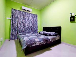 a bedroom with a bed in a room with green walls at Izzara Iskandar Puteri Homestay Gelang Patah in Gelang Patah