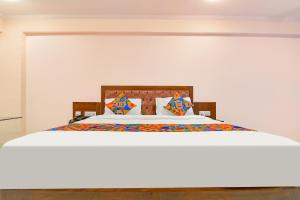 FabHotel JBS Heritage في جايبور: غرفة نوم مع سرير أبيض كبير مع وسائد ملونة