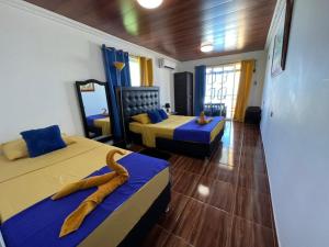 a room with two beds with blue and yellow at Posada Ashanty in Providencia