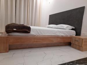 een slaapkamer met een bed met een houten bedframe bij Ashoka Resort & Banquets in Begusarai