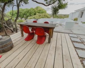 a wooden table with red chairs on a deck at Rooisee in Yzerfontein
