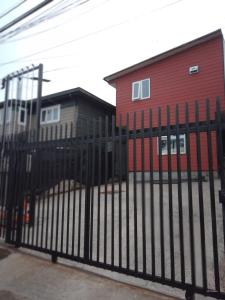 een zwart metalen hek voor een rood gebouw bij Apartamento en pto Montt in Puerto Montt