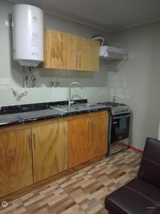 een keuken met houten kasten, een wastafel en een fornuis bij Apartamento en pto Montt in Puerto Montt