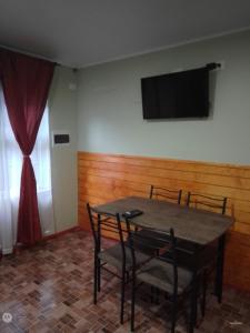 een tafel met stoelen en een televisie aan de muur bij Apartamento en pto Montt in Puerto Montt