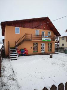 a building with snow on the ground in front of it at Casa Daiana - Toplița in Topliţa