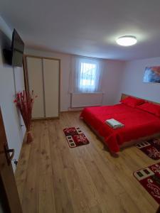 1 dormitorio con cama roja y suelo de madera en Casa Daiana - Toplița, en Topliţa