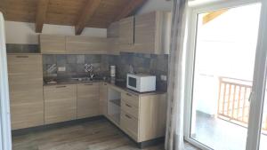 a kitchen with wooden cabinets and a white microwave at CASA RAINA in Castelfondo