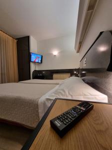 維琴察的住宿－維琴察克里斯蒂娜城市酒店，一间房间,配有一张床和一张桌子上的遥控器