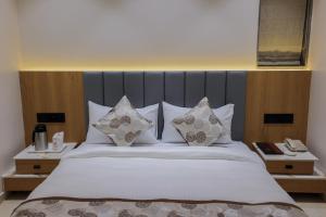 a bedroom with a large bed with white sheets and pillows at Hotel Aditya Mansingh Inn in Somnath