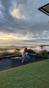 a woman sitting on top of a grassy hill at Chill & View in Ban Huai Phai