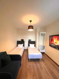 two beds in a room with a couch and a tv at Centre Premium in Pärnu