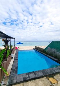 a swimming pool with the beach in the background at Lembongan Made Inn in Nusa Lembongan