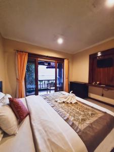 a bedroom with a large bed with a large window at Lembongan Made Inn in Nusa Lembongan