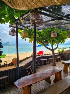 una terraza de madera con mesas y sillas en la playa en Lembongan Made Inn, en Nusa Lembongan