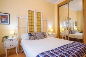 1 dormitorio con 1 cama blanca grande y espejo en Precioso Apartamento San Juan de la Palma, Parking Optional, en Sevilla