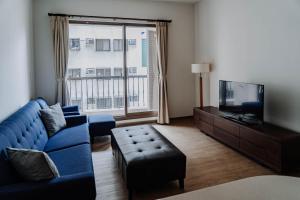 uma sala de estar com um sofá azul e uma televisão em LAR Suite em Taichung