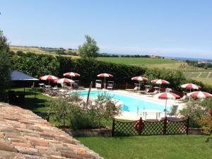 a swimming pool with red umbrellas and a pool at Agriturismo Papaveri e Papere in Saludecio