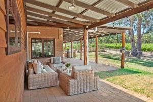 an outdoor patio with wicker chairs and a wooden roof at Island Brook Estate Vineyard and Chalets in Yelverton