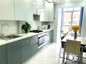 uma cozinha com armários brancos e uma mesa com cadeiras em Comfortable apartment in a complex Great Britain em Lviv