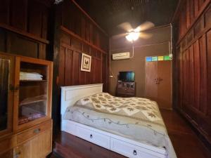 a bedroom with a bed in a room with wooden walls at Ruennakornin Homestay in Ban Bang Kho