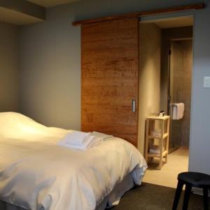 a bedroom with a white bed and a wooden wall at arita huis in Arita