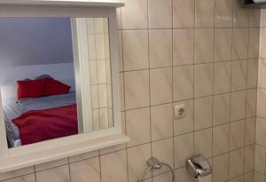 a bathroom with a mirror and a bed with a red pillow at Kirchstraße 71 in Fell