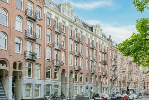 un grand bâtiment en briques avec des voitures garées devant lui dans l'établissement Central Rooftop Terrace Guest Suite, à Amsterdam