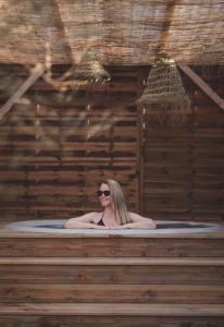 Eine Frau in einer Badewanne in einem Holzgebäude in der Unterkunft Le Clos Bleu - Gite Rural in Schillersdorf