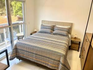 1 dormitorio con cama con almohadas y ventana en Sensacional duplex novo na praia dos Ingleses, en Florianópolis