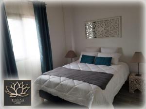 a bedroom with a large white bed with blue pillows at Téréva Lodge - La villa de standing in Cilaos