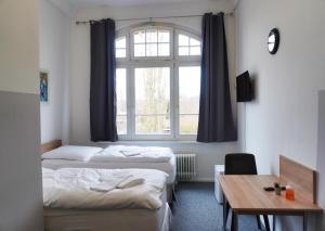 ベルリンにあるMotel Home Wittenauのベッド3台、テーブル、窓が備わる客室です。