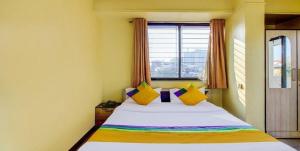 a bedroom with a bed with colorful pillows and a window at Coronet Luxurious Apartment in Pune