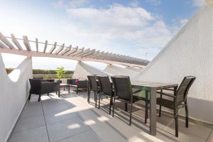 um pátio com uma mesa e cadeiras no telhado em Double Jeu- NATURISTE VILLAGE-SPA-Clim-2 BEDROOM-Parking-90m2 em Cap d'Agde