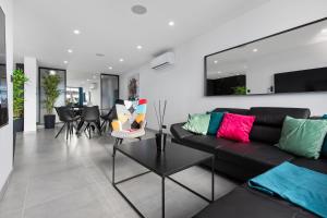 uma sala de estar com um sofá preto e cadeiras em Double Jeu- NATURISTE VILLAGE-SPA-Clim-2 BEDROOM-Parking-90m2 em Cap d'Agde