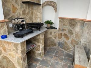 cocina con parrilla y pared de piedra en Casa rural Maila en Malpartida de Cáceres